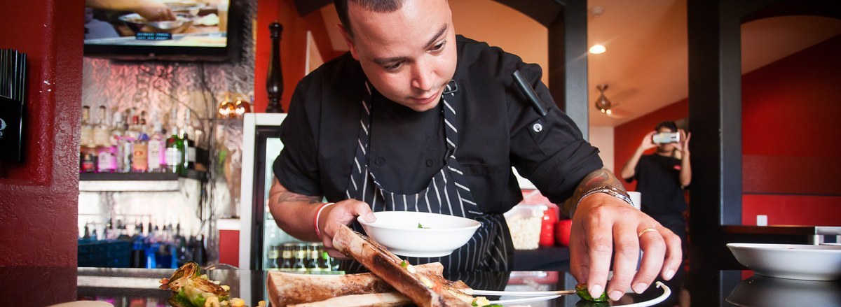 A chef plating a dish at the pass